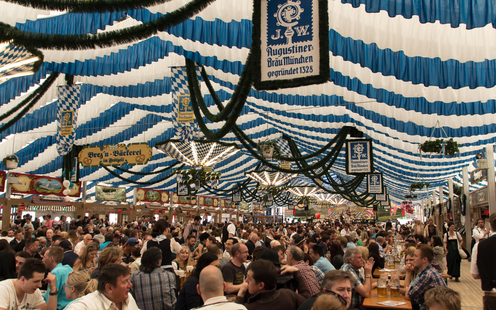 the interior of a tent for Oktoberfest in Munich, Germany, filled with people drinking and eating at tables